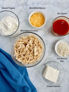 ingredients for chicken salad laid out in bowls on a marble counter top with blue towel