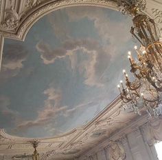 a chandelier hanging from the ceiling in a room with a sky painted on it