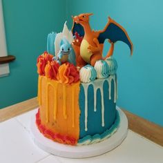 a birthday cake decorated with icing and fondant dragon figurines on top