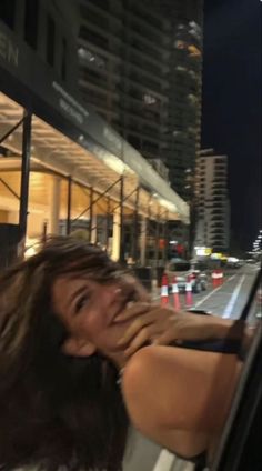 a woman sitting in the drivers seat of a car with her hand on her face