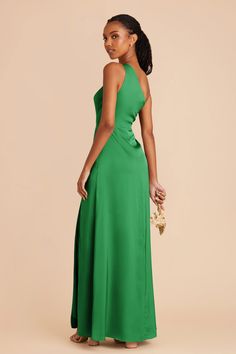 a woman in a long green dress with her back to the camera, looking down