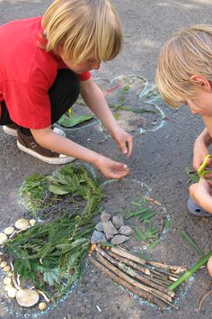 two young boys sitting on the ground looking at plants