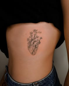 a woman's stomach with a heart and flowers tattoo on the side of her body