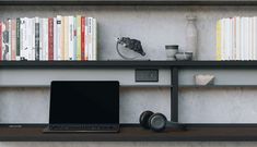 an open laptop computer sitting on top of a wooden desk next to a bookshelf