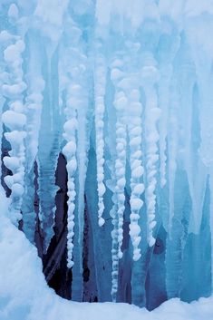 an ice cave with icicles hanging from it's sides and snow on the ground