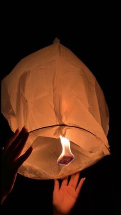 someone holding a paper lantern in their hand with the light on it's side