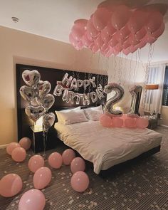 balloons are floating in the air above a bed with pink and silver decorations on it