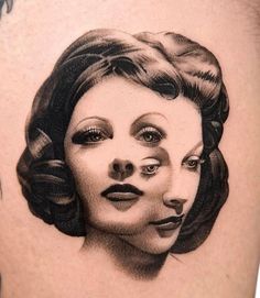 a woman's face is shown in black and grey ink on the back of her thigh