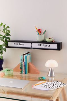 there is a desk with books and a laptop on it next to a potted plant