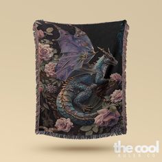 a blue dragon sitting on top of a flowery blanket with fringes around it