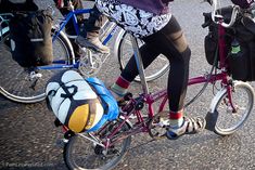 two people riding bikes with bags attached to the handlebars and saddlebags on their backs