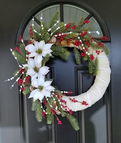 a wreath with white flowers and greenery on the front door