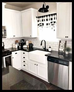 a kitchen with white cabinets and black counter tops, stainless steel dishwasher in the center