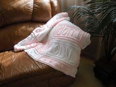 a crocheted blanket sitting on top of a brown leather couch next to a potted plant