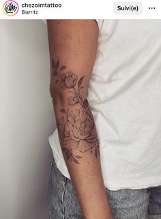 a man with a flower tattoo on his arm and hand is standing in front of a white wall