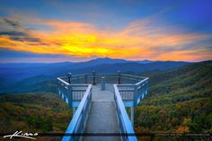 a walkway leading to the top of a mountain at sunset with mountains in the background