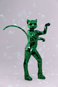 a green cat figurine standing on its hind legs in front of a white background