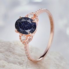 a diamond and blue sapphire engagement ring on top of a white rock with diamonds surrounding it