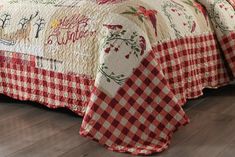 a red and white checkered bedspread on a bed with a wooden floor