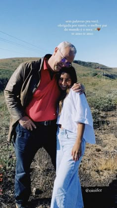 an older man standing next to a young woman on top of a grass covered field