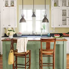 a kitchen with two stools in front of an island and three lights hanging from the ceiling