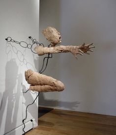 an art piece is hanging on the wall next to a wooden sculpture with chains attached to it