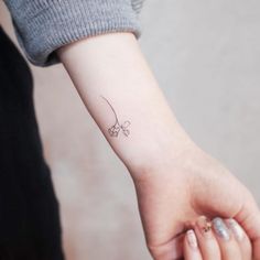 a woman's arm with a small flower tattoo on the left side of her wrist