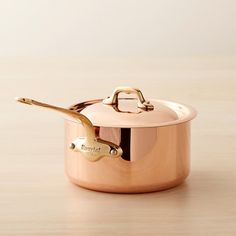 a copper colored pot with a lid on a wooden table