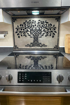 a stove top oven sitting inside of a kitchen next to a wall with a tree on it