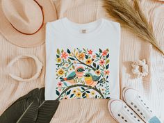 Elevate your wardrobe with this whimsical birds and flowers t-shirt, featuring a stunning nature-inspired graphic. This colorful botanical art print adds a cute and vibrant touch to any outfit. *🌿 High-quality graphic t-shirt with a whimsical bird and floral design *🐦 Made from soft, comfortable fabric perfect for everyday wear *🌸 Available in multiple sizes and colors to suit your style *👕 Durable print that stands up to washing and regular use *🎁 Great gift idea for bird lovers, nature enthusiasts, and art fans *🛒 Ideal for casual outings, nature walks, and as a statement piece *💧 Easy care instructions: machine washable and tumble dry low Comfort Colors introduces the "Comfort Colors 1717" garment-dyed t-shirt; a fully customizable tee made 100% with ring-spun cotton. The soft-wa Summer Crew Neck T-shirt With Bird Print, Summer Cotton Tops With Bird Print, Casual Summer T-shirt With Bird Print, Whimsical Birds, Floral Pattern Shirt, Stunning Nature, Cute Bird, Birds And Flowers, Pattern Shirt