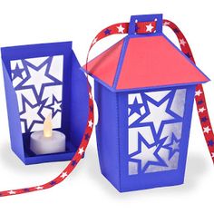 a blue lantern with red, white and blue stars on it next to a candle