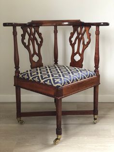 an antique wooden chair with blue and white patterned seat pad on the back, in front of a white wall