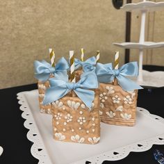 three small brown bags with blue bows and candles