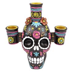 a colorful skull vase with three cups on it's head and two candles in the middle