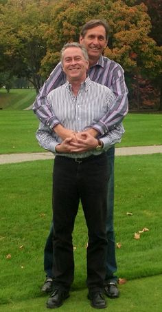 two men standing in the grass with their arms around each other