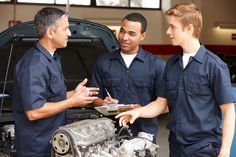 two mechanics talking to each other in front of a car with the engine on it's hood