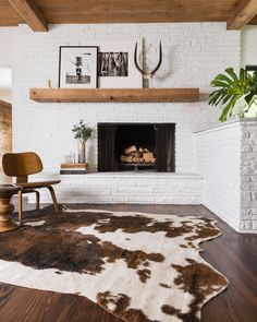 a living room with a white brick fireplace and black and white cowhide rug on the floor