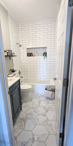 a bathroom with white tile and gray cabinets