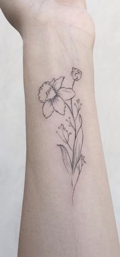 a small flower tattoo on the left side of the arm, with leaves and flowers around it