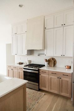 a kitchen with white cabinets and black stove top oven in the center, along with an area rug on the floor