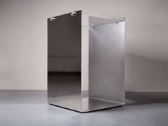 an empty metal box sitting on top of a gray floor in front of a white wall