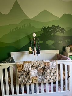 a baby crib in front of a green mountain mural