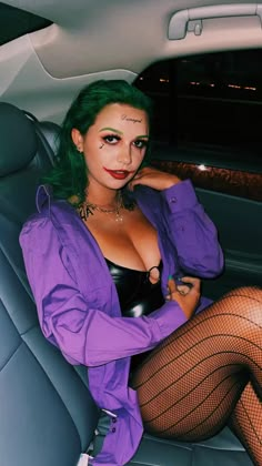 a woman with green hair sitting in the back seat of a car wearing fishnet stockings