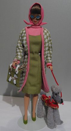 a barbie doll holding a dog on a leash