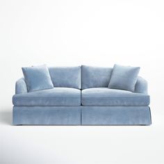 a blue couch with two pillows on the back and one arm folded over it's head