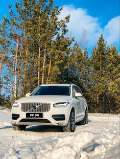 a white car parked in the snow near some trees