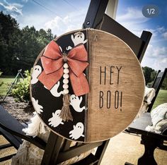 a wooden sign that says hey boo with ghostes and a red bow on it