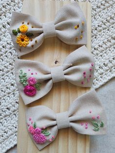 three bows with flowers on them sitting on top of a wooden board