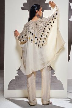 Ivory cape shirt embellished with mirror work adornments. Comes with solid straight pant. - Aza Fashions Festive Kaftan With Mirror Work And Cape Sleeves, Festive Mirror Work Kaftan With Cape Sleeves, White Mirror Work Kaftan For Festive Occasions, White Kaftan With Mirror Work For Eid, Eid Kaftan With Mirror Work And Cape Sleeves, Designer Embellished White Palazzo Set, Embellished White Palazzo Set For Designer Wear, White Embellished Palazzo Set For Designer Wear, Festive White Embellished Palazzo Set