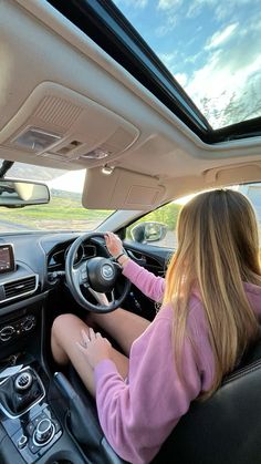 a woman driving a car while holding the steering wheel